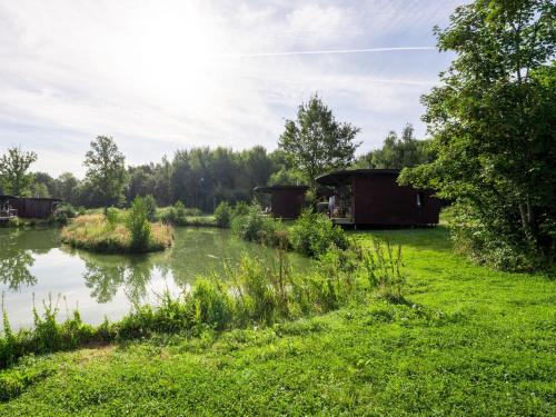 a cabin next to a river with trees and grass at Charming Antoing Bungalow in Antoing