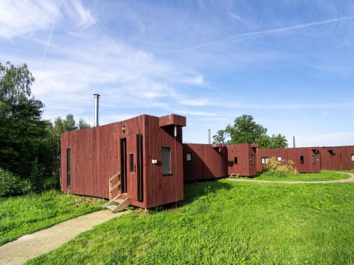 a row of red buildings in a field of grass at Nature Escape Bungalow in Antoing