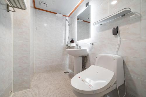a bathroom with a toilet and a sink and a mirror at Sokcho Ritz Hotel in Sokcho