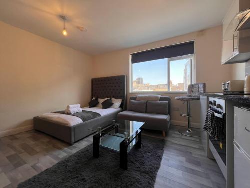 a living room with a couch and a window at Haven Homes - Central Luton Studio Apartments in Luton