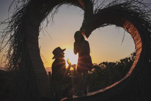 two people standing under a heart shaped arch with the sunset at Brisa Del Valle Hotel Boutique in Valle de Guadalupe