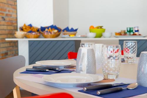 a table with plates and glasses on top of it at Hôtel des 4 Ours in Aragnouet