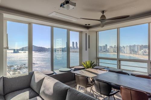 a living room with a couch and a table with chairs at Meomulda Ga Gwangan Poolvilla in Busan
