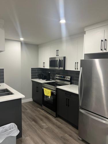 a kitchen with white cabinets and a stainless steel refrigerator at Beautiful suite in Balzac