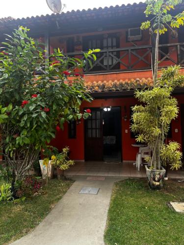 een rood huis met een rode deur en bomen bij Casa Duplex com 02 suites completa em Condomínio com Piscina , Sauna , churrasqueiras, deck podendo parar embarcações, próximo as Praias das Conchas e Peró e também linda Ilha do Japônes in Cabo Frio