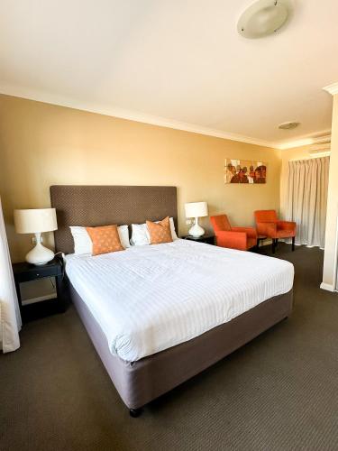 a bedroom with a large bed and orange chairs at Sundowner Motel Hotel in Whyalla