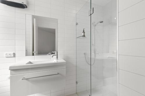 Un baño blanco con lavabo y ducha. en Tenby Apartments, en Wanaka