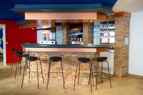 a bar with stools in front of a brick wall at Hôtel des 4 Ours in Aragnouet