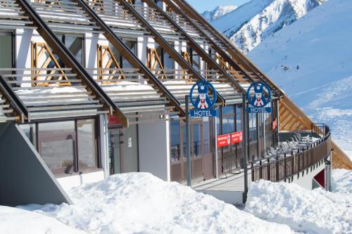 a building with snow on the ground in front at Hôtel des 4 Ours in Aragnouet