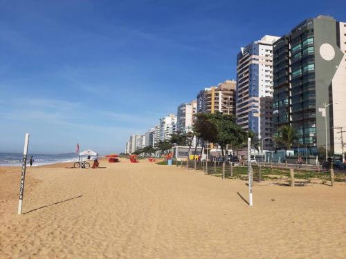 a sandy beach with tall buildings and the ocean at 2qts, 2 AR, 3 TV, Perto da Praia, Garagem in Itaparica