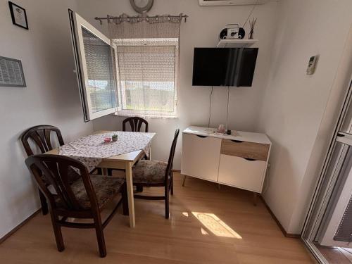 a dining room with a table and chairs and a television at Apartments Strahija in Barbat na Rabu