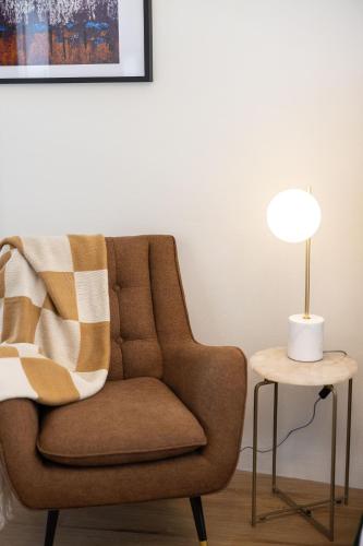 a brown chair sitting next to a table with a lamp at Peppertree Apartments in Sale