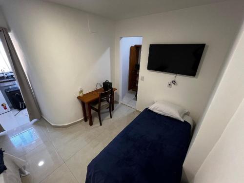 Un dormitorio con cama, escritorio y televisión. en Flat completo para até 4 pessoas no Vidigal - RJ, en Río de Janeiro