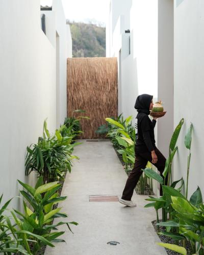 a person walking down a hallway with a plate of food at Suku Lifestyle Hotel & Villas in Selong Belanak