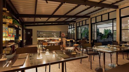 ein Restaurant mit Tischen und Stühlen in einem Raum in der Unterkunft The StandardX, Bangkok Phra Arthit in Bangkok