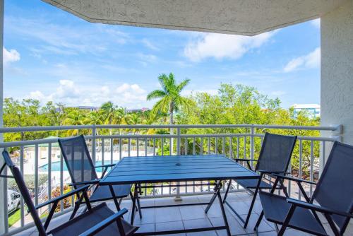 a patio with a blue table and chairs on a balcony at The Barbados -Bright Condo w Pool in Key West