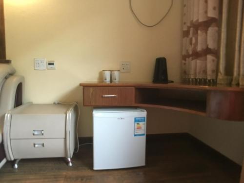 a small white refrigerator in a room with a desk at Moganshan Bamboo View Guesthouse in Deqing