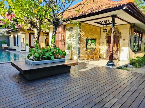 a house with a wooden deck and a swimming pool at Rabasta Enjoy Kuta in Denpasar