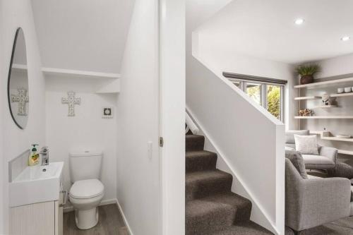 Baño blanco con aseo y escalera en Convenient Urban Townhouse 2 carparks available, en Christchurch