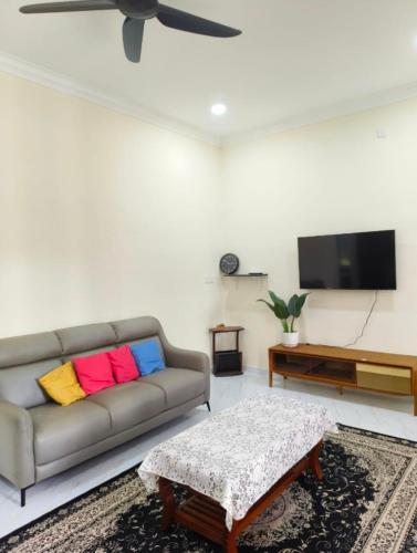 a living room with a couch and a flat screen tv at Homestay Merah Jambu UTHM in Parit Raja