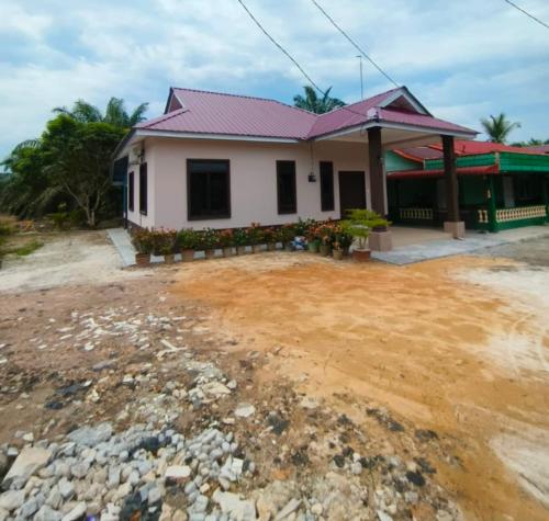 a house with a dirt yard in front of it at Homestay Merah Jambu UTHM in Parit Raja
