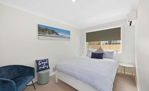 a bedroom with a bed and a chair and a window at Azul Blue at Shellys in Port Macquarie