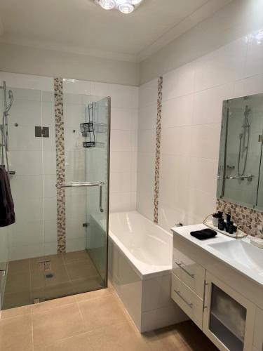 a bathroom with a shower and a tub and a sink at Lbarza Charming Central 2BR Townhouse in Shepparton