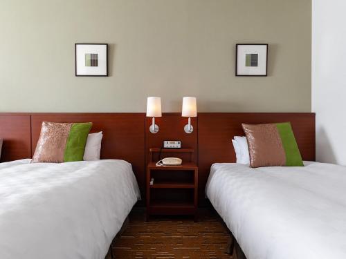 two beds sitting next to each other in a room at Akita Castle Hotel in Akita