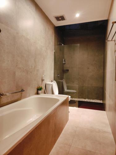 a bathroom with a tub and a toilet and a sink at Rabasta Enjoy Kuta in Denpasar