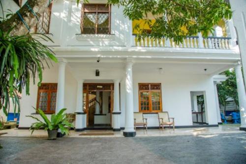 una casa blanca con dos sillas delante en Blue Swan Inn, en Unawatuna