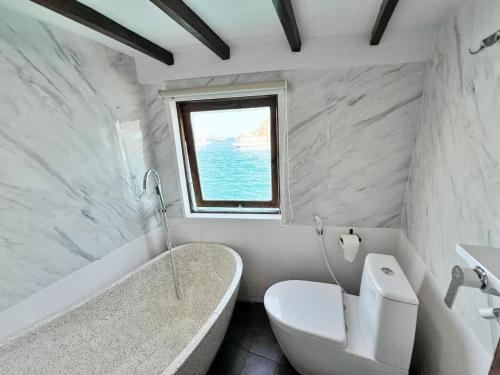 een badkamer met een bad, een toilet en een raam bij Leticia Liveaboard in Labuan Bajo