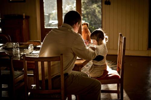 a man sitting at a table with a little girl at Three Tree Hill Lodge in Bergville