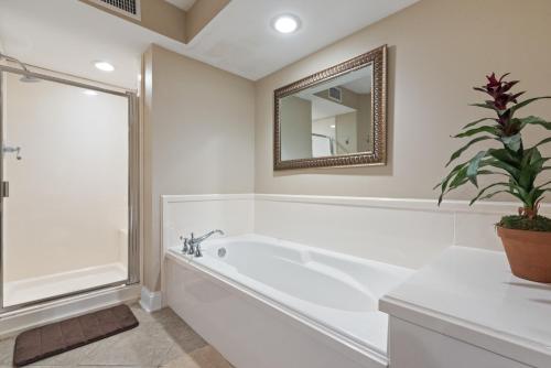 ein weißes Bad mit einer Badewanne und einem Spiegel in der Unterkunft Fun 2 bed/2 bath condo with pool on Biloxi Beach in Biloxi