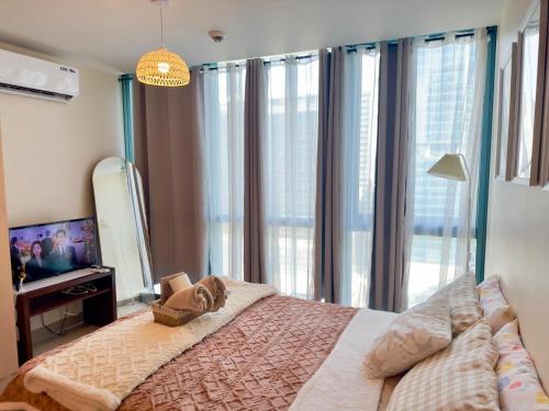 a bedroom with a large bed and a television at Cozy 1BR Condo with Uptown Mall View - BGC Zen Suite in Manila