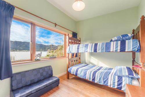 a bedroom with two bunk beds and a window at Pukeko Cottage - Marlborough Sounds Retreat in Linkwater