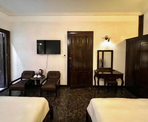 a hotel room with two beds and a desk and a television at The Manor Villas Da Lat in Xuan An