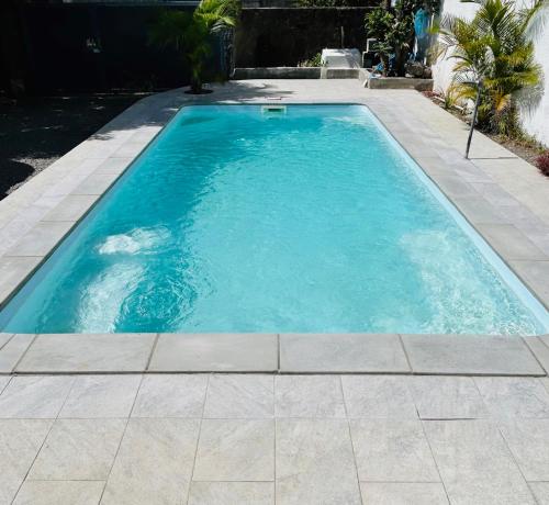 a swimming pool with blue water in a yard at Villa Ellapen in Pereybere