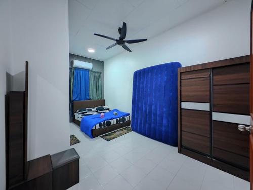 a bedroom with a blue bed and a ceiling fan at Homestay Last World Tambun in Kampong Batu Lapan