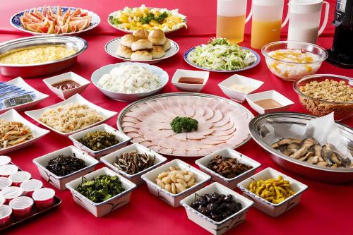 une table rouge surmontée de nombreux plats de nourriture dans l'établissement ホテルにれの樹, à Hakuba