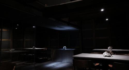 a room with tables and chairs in a dark room at ひがし茶屋街らしく金沢 Hotel Rashiku kanazawa in Kanazawa