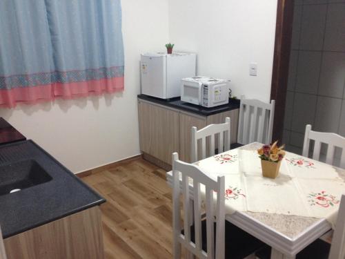 a kitchen with a table and chairs and a microwave at Pousada Suite Master Bella Mar in Penha