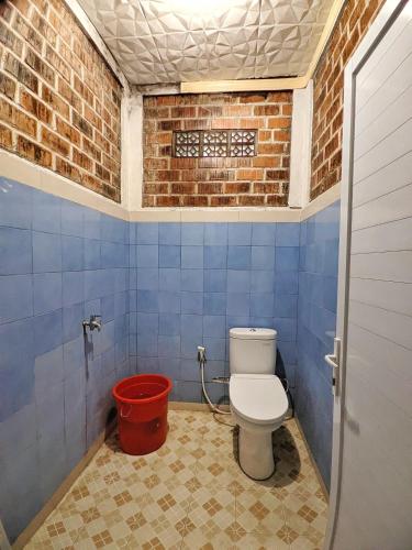 a bathroom with a toilet and a red bucket at Omah Trasan Pangrango by ABM in Bogor
