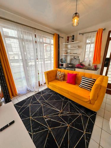 a living room with an orange couch and a kitchen at Classy Studio Apartment racecourse Gardens in Nairobi