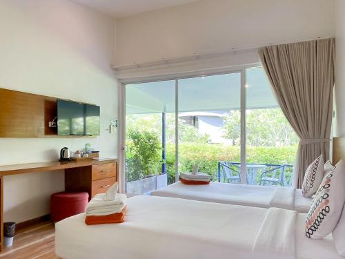 a bedroom with two beds and a large window at Kata Forte Resort in Kata Beach
