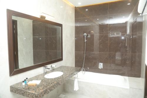 a bathroom with a sink and a tub and a mirror at Swarg Hotel in Sāhīwāl