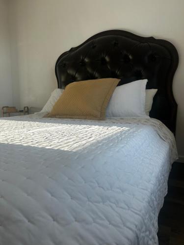 1 cama con cabecero negro y sábanas y almohadas blancas en Near Red Mountain park, en Mesa