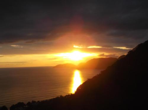 a sunset over the ocean with the sun in the sky at Vila Lia in São Sebastião