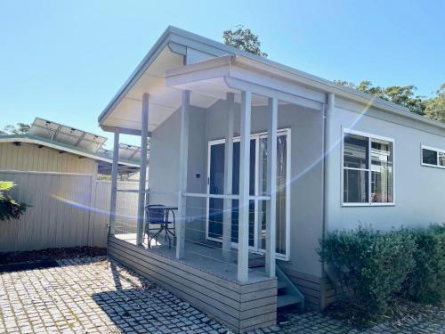 a small white house with a porch and a chair at Jervis Bay Mariners in Huskisson