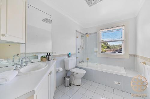 a bathroom with a sink and a toilet and a bath tub at Greenwich Luxury near WharfTrainCBD steps to Sea in Sydney