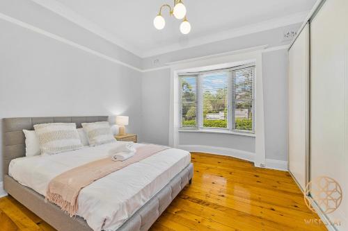 a white bedroom with a large bed and two windows at Greenwich Luxury near WharfTrainCBD steps to Sea in Sydney